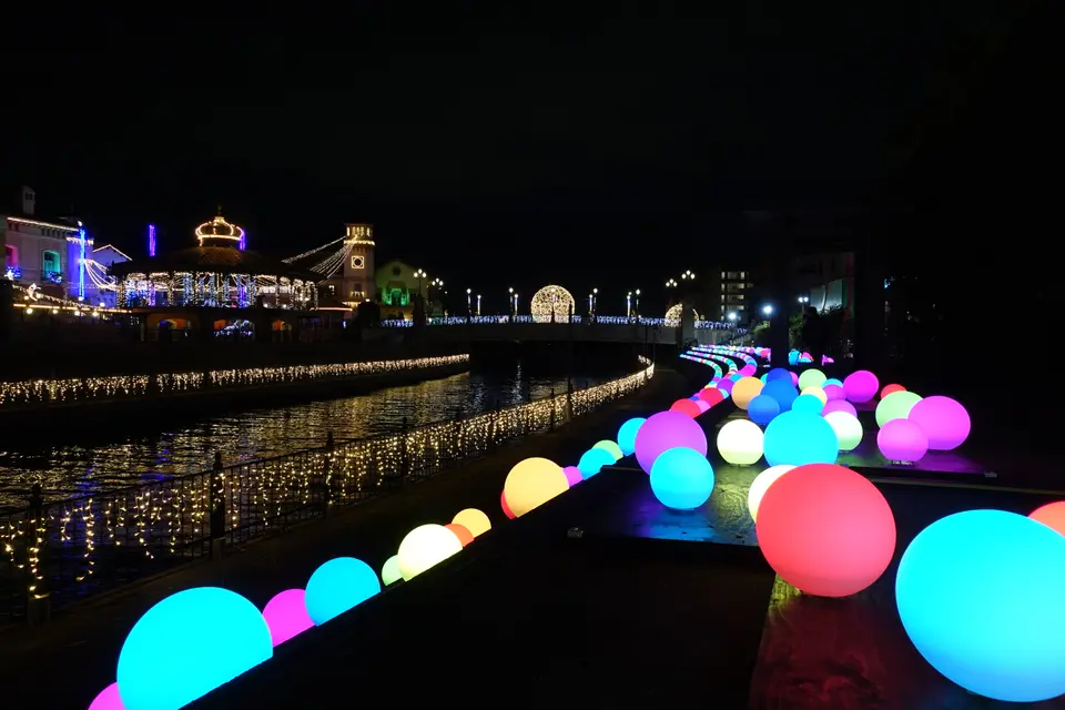 「Drop of Light」の会場。運河沿いに連なる色とりどりの光る球体と、ライトアップされた建物群の夜景