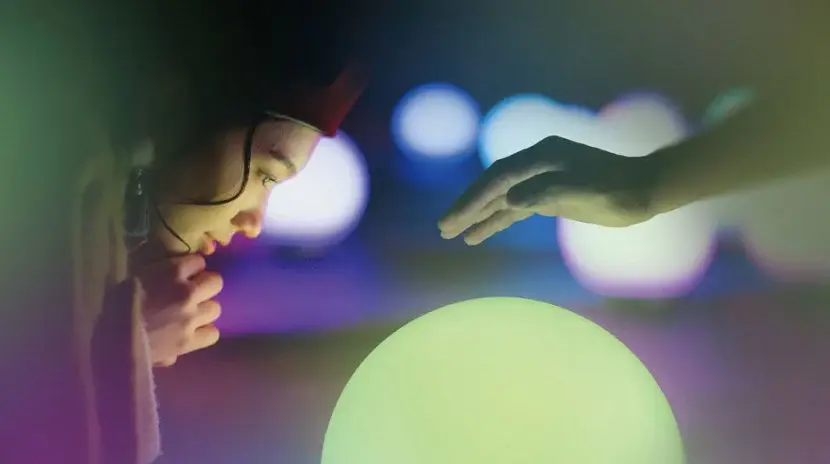 光る球体に手を伸ばす来場者。触れると光の波紋が広がるインスタレーション「Drop of Light」