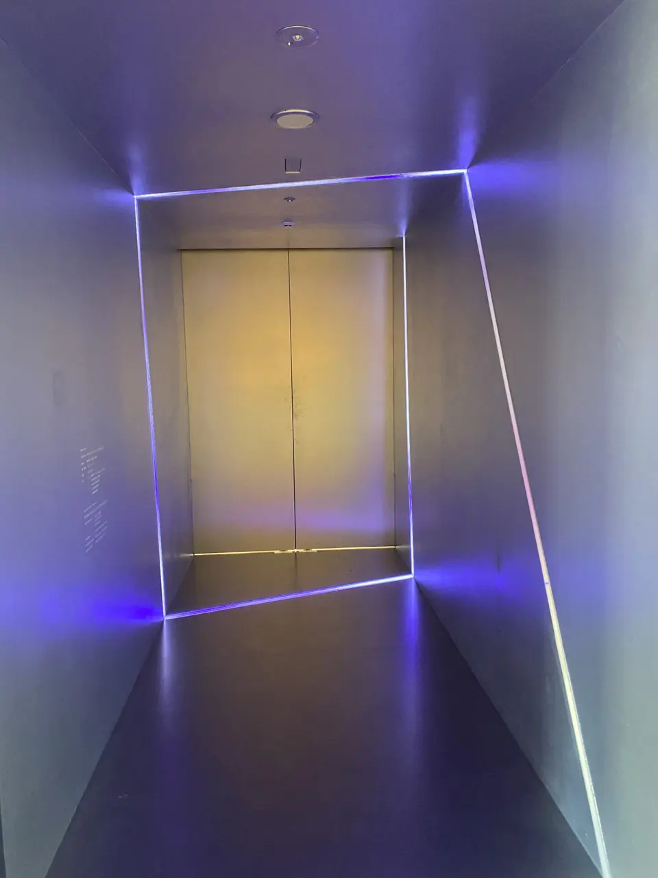 Personal Wellness Clinic MARUNOUCHIのエレベーターホール。紫の光の線が縁取る、宇宙感と浮遊感を宿す照明演出
