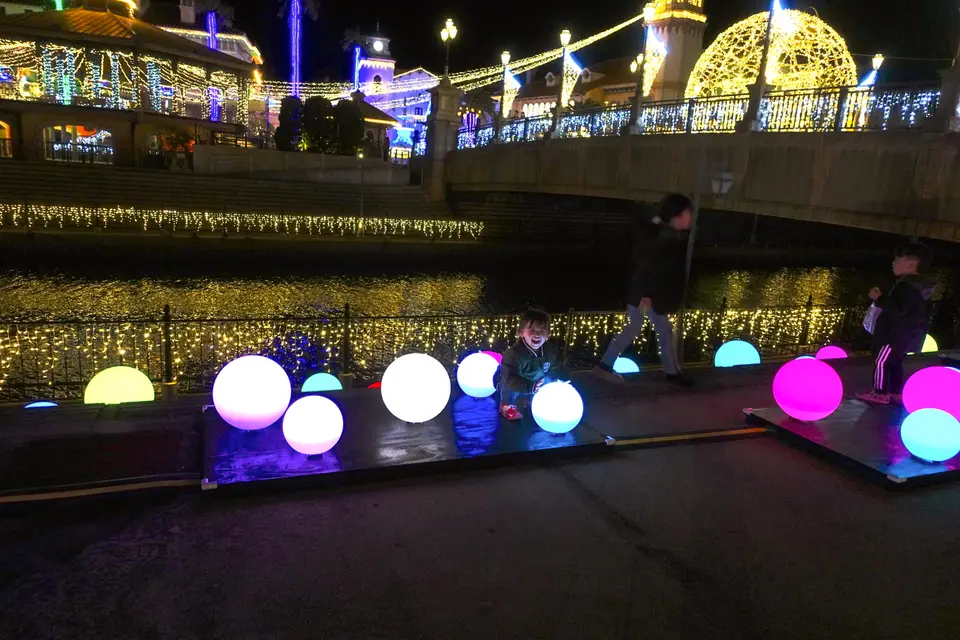 光る球体に囲まれて座る子供。「Drop of Light」がつくる夜の光の道