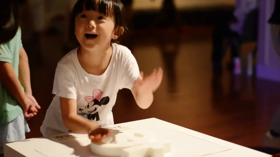 「あ」の立体物に触れて笑顔を見せる来場者の子供
