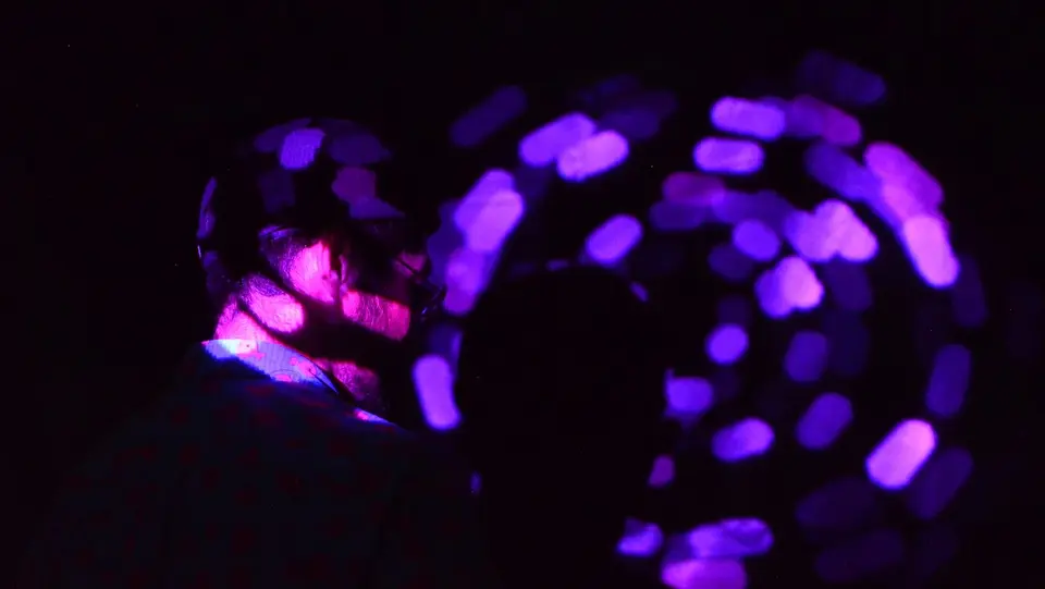 「Distance」の展示風景。暗闇の中、紫色の光の輪に照らされる体験者の様子