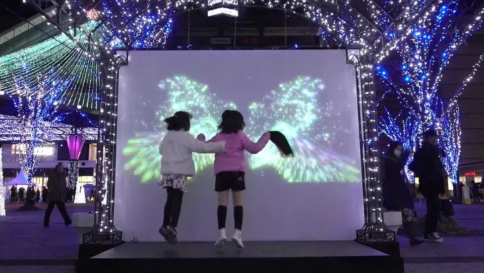「インタラクティブ フォトスポット」で天使の羽の映像に合わせて遊ぶ子供たちの様子