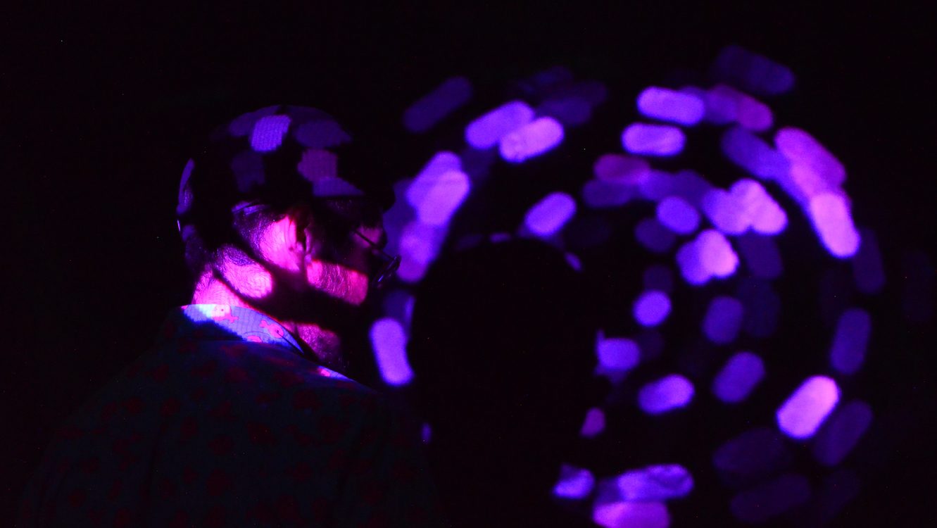 「Distance」の展示風景。暗闇の中、紫色の光の輪に照らされる体験者の様子